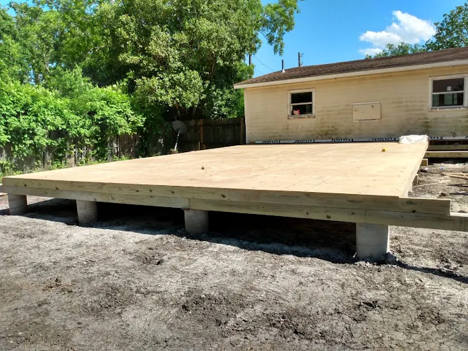 New wood subfloor platform built on a row of concrete piers, raised above grade