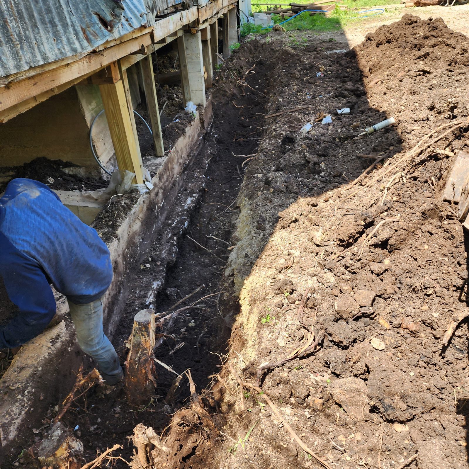 Deep excavation along a foundation beam with worker accessing under the structure